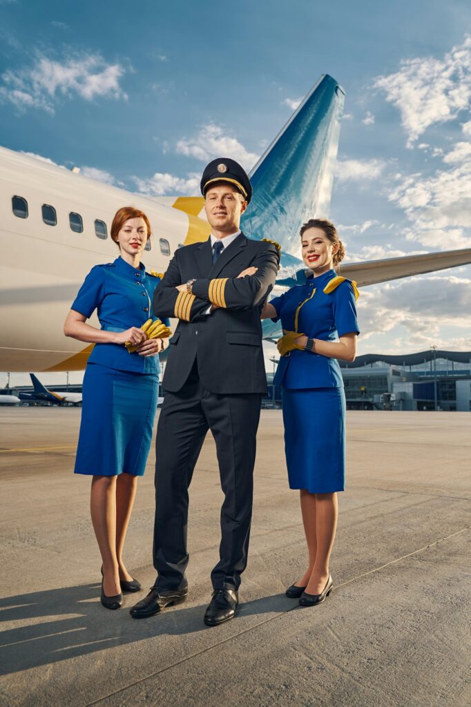 Cute airline captain and air hostesses standing at the airdrome