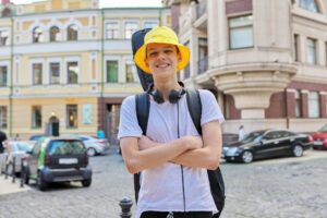 Portrait of creative handsome guy in yellow panama hat with guitar in case