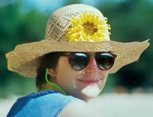 Summer fashionable woman with sunglasses wearing a wide brimmed sunflower straw hat