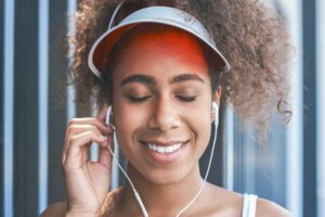 Young woman in tennis visor putting on earphones free style on t